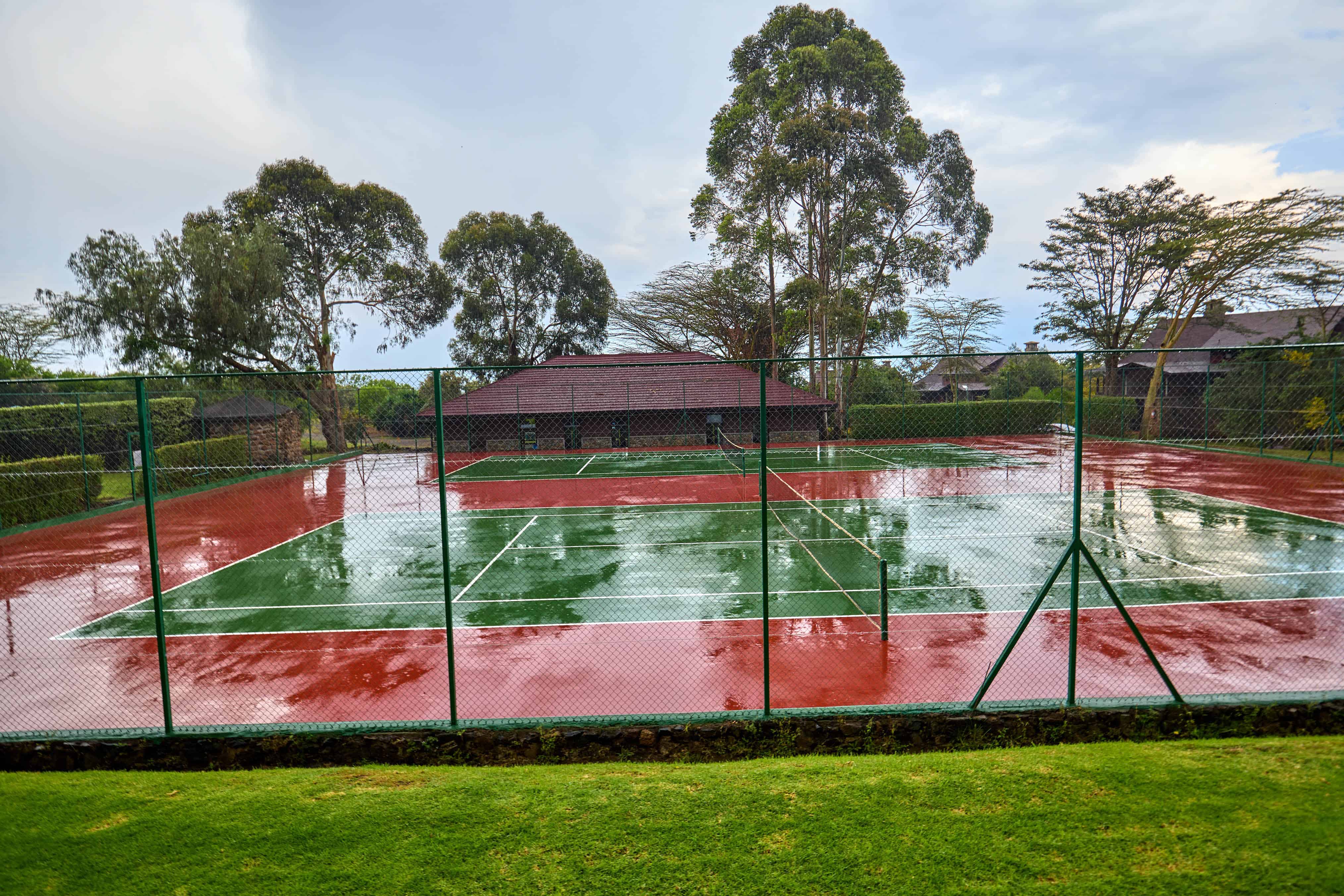 Tennis court with green and red surfaces surrounded by fencing
