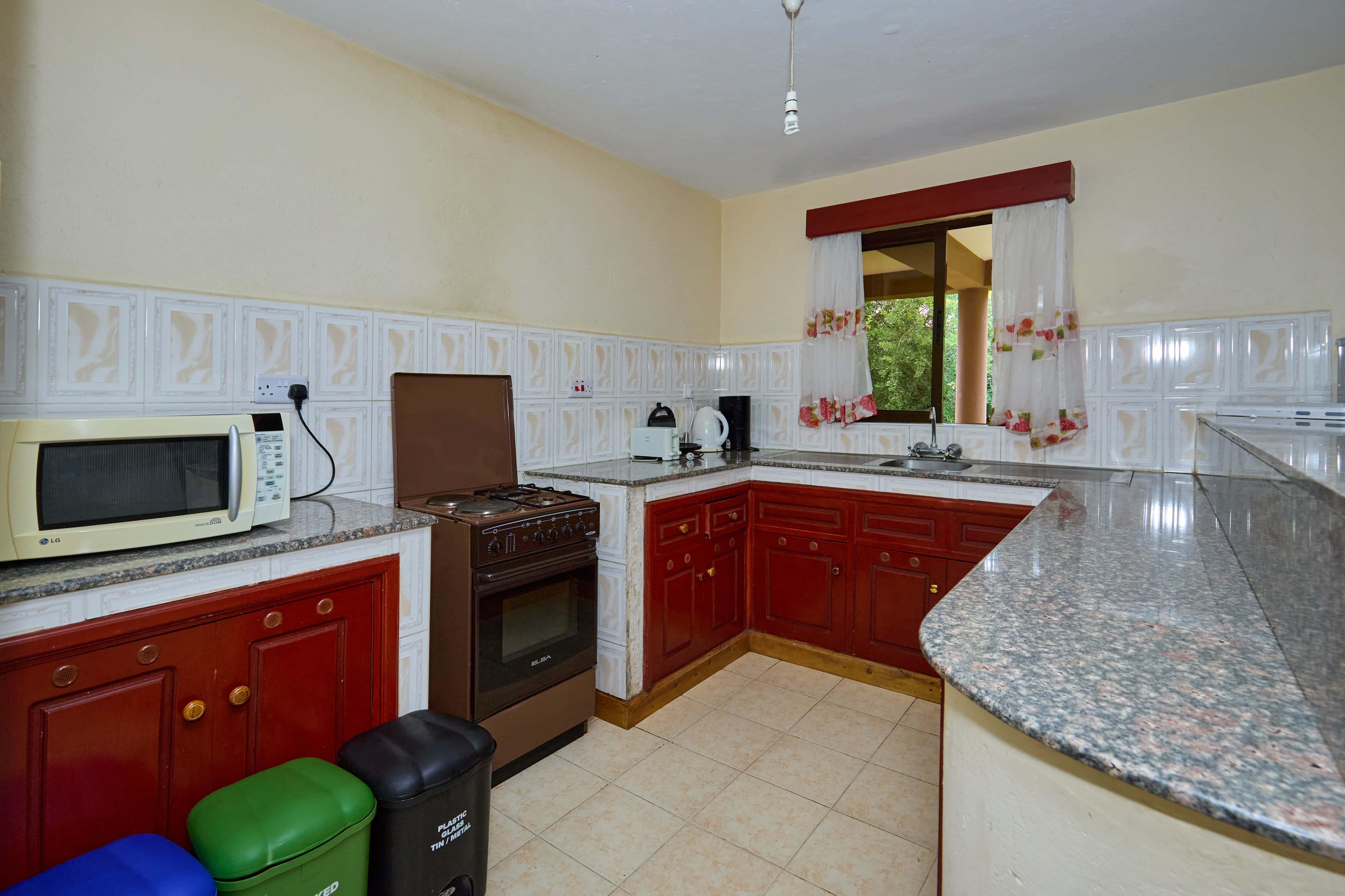 Fully equipped kitchen with red cabinets and granite countertops
