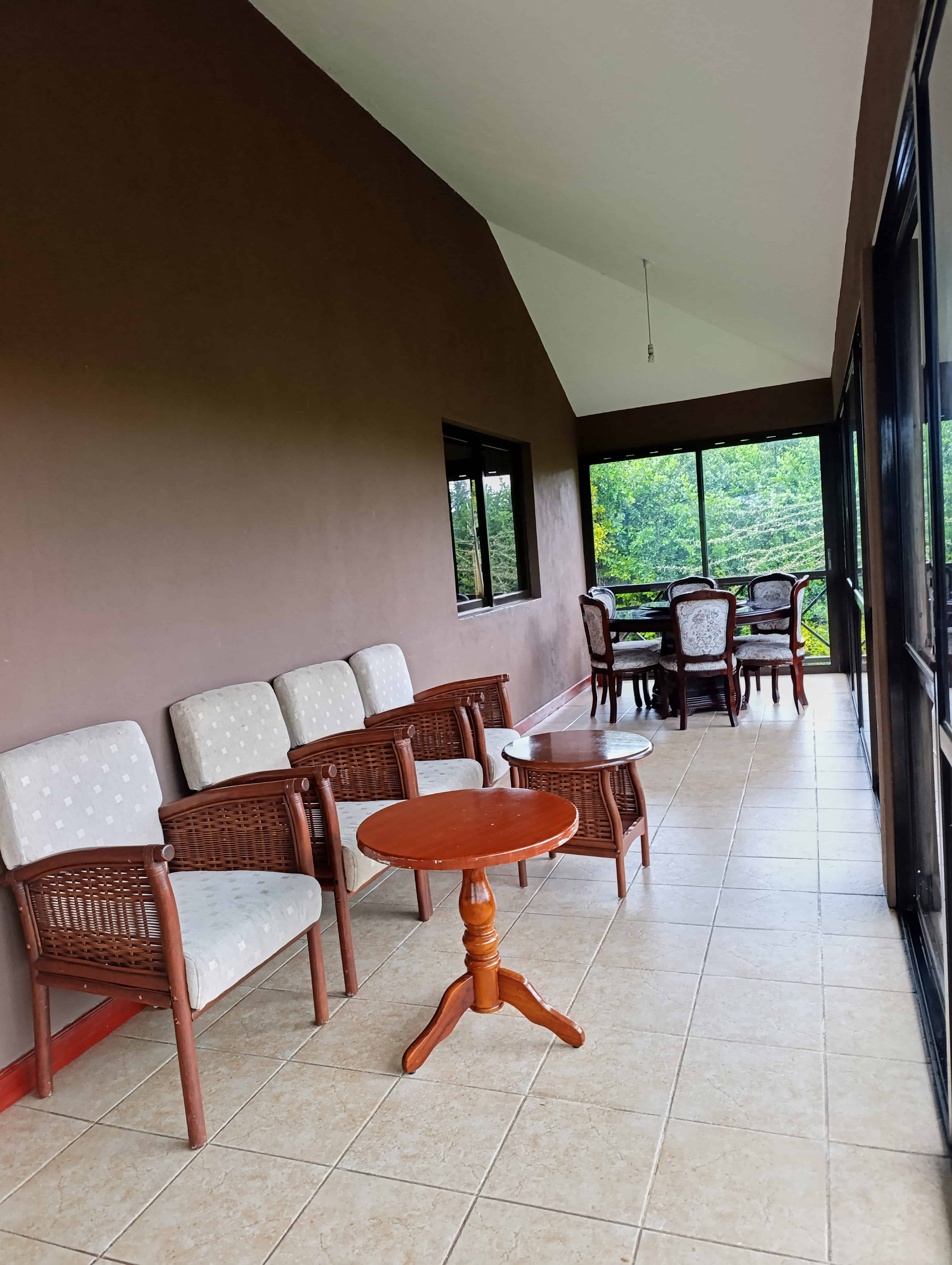 Covered outdoor terrace with wicker furniture and forest views